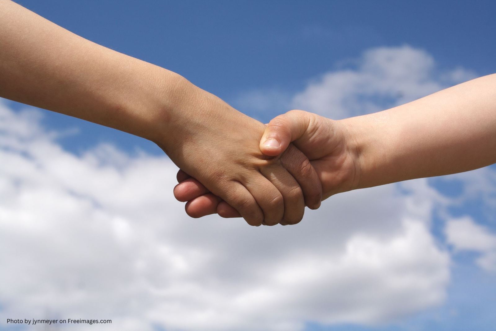 hands shaking with clouds in sky background